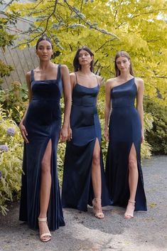 three women in blue dresses standing next to each other with their legs slited out