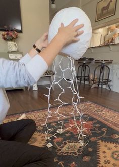 a woman is holding a large white ball on top of a wire structure in the middle of a living room