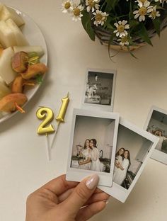 a person holding up four photos with the number twenty two on them and flowers in the background