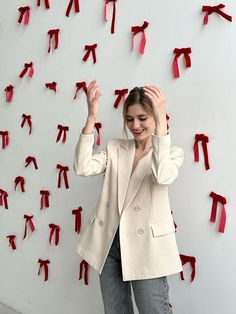 a woman standing in front of a wall with red ribbons attached to it and her hands up