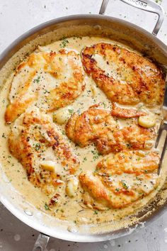 a skillet filled with chicken and gravy on top of a white table