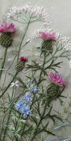 some pink and blue flowers are on a table cloth with green stems in the middle