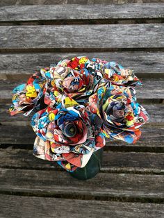 a bouquet of paper flowers sitting on top of a wooden bench