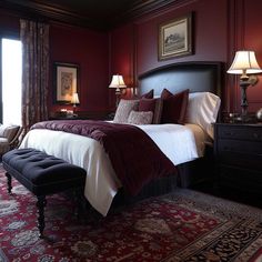 a bedroom with red walls and carpeted flooring, along with two lamps on either side of the bed