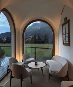 a living room filled with furniture next to an open window overlooking a green field and mountains