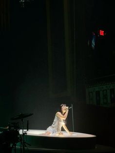 a woman sitting on top of a white boat in the middle of a dark room