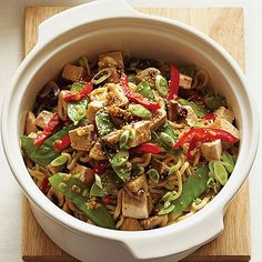 a white bowl filled with food on top of a wooden cutting board