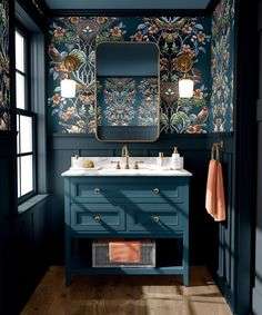 a bathroom with dark blue walls and floral wallpaper on the vanity, along with a gold framed mirror