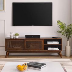 a flat screen tv sitting on top of a wooden entertainment center in a living room