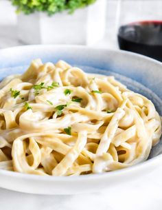 a white bowl filled with pasta and garnished with parsley