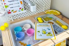 there is a tray with lemonade and cups on the counter next to a sign