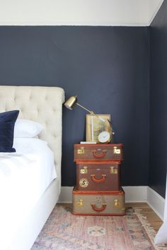 two suitcases stacked on top of each other in front of a bed with blue walls