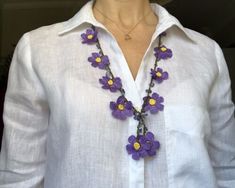 a woman wearing a white shirt and purple flower necklace