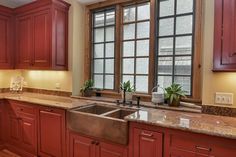 a kitchen with red cabinets and marble counter tops