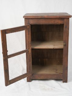 an old wooden cabinet with chicken wire in the front and side doors open to reveal it's contents