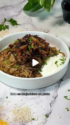 a white bowl filled with rice and meat on top of a marble counter next to vegetables