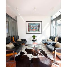 a living room filled with furniture and a cowhide rug on the floor in front of a window