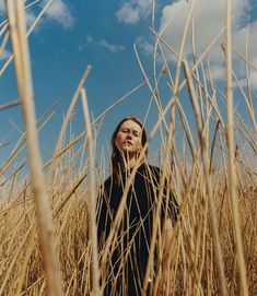 a woman standing in the middle of a wheat field