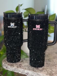 two black sparkle tumblers sitting on top of a counter