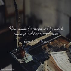 a desk with an old book, quill and pen on it that says you must be prepared to work always without applause