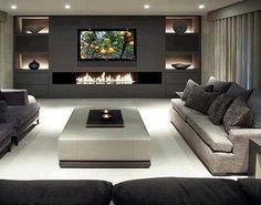 a large living room with couches and a television mounted on the wall in front of a fireplace