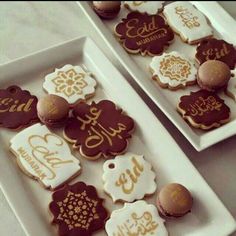 two white trays filled with decorated cookies on top of a table next to each other