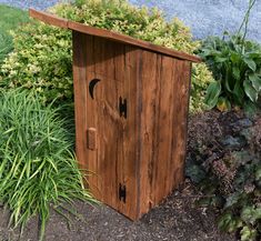 a wooden outhouse sitting next to some plants