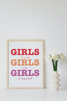 there is a vase with flowers on the shelf next to a framed poster that says girls i've got girls and they are my most