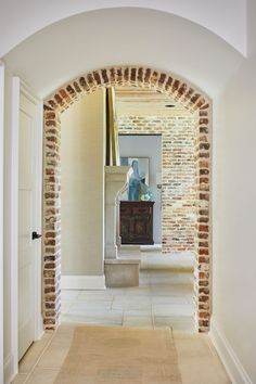 an archway leading to a living room with a table and vase on the end shelf