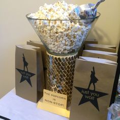 popcorn in a glass bowl on top of a table next to small bags with the words just you went