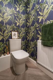 a bathroom with blue and green wallpaper on the walls, toilet and bathtub