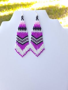 purple and white beaded earrings sitting on top of a table