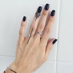 a woman's hand with black nail polish and ring tattoos on her left wrist