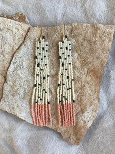 two pairs of beaded earrings sitting on top of a rock