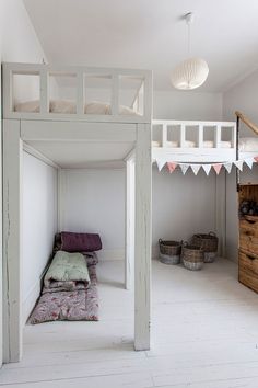 a bunk bed in the middle of a room with white walls and wooden flooring