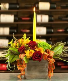 a vase filled with flowers next to a lit candle