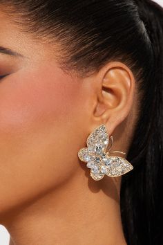 a close up of a woman's face wearing large earrings with butterfly design on them