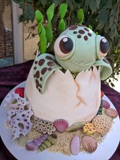 a cake decorated to look like a sea creature with eyes and hands sticking out from inside an egg shell