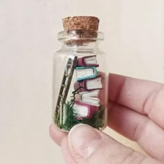 a hand holding a tiny glass bottle filled with books