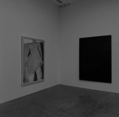 two black and white paintings hanging in an empty room