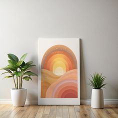 three potted plants sit on the floor in front of a framed art print with an abstract rainbow design