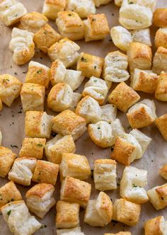 the bread is cut into cubes and placed on a piece of parchment paper with herbs sprinkled on top