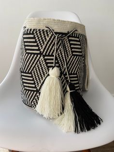 a black and white bag with tassels on it sitting on top of a chair