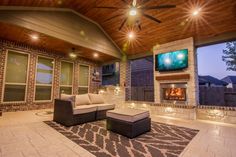 an outdoor living room with fireplace and ceiling fan