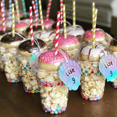 cupcakes and marshmallows are arranged in plastic cups with candy sticks