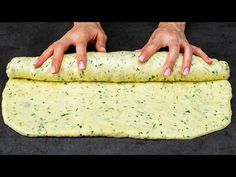 two hands reaching for an uncooked pizza dough on a black surface with dark background