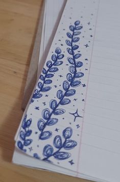 two notebooks with blue designs on them sitting on a wooden table next to each other