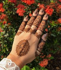 a woman's hand with henna tattoos on it and flowers in the background