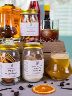 three jars filled with different types of food on top of a table next to an orange slice