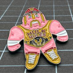 a pink and gold wrestling wrestler pin sitting on top of a black tile floor next to a blue tiled wall